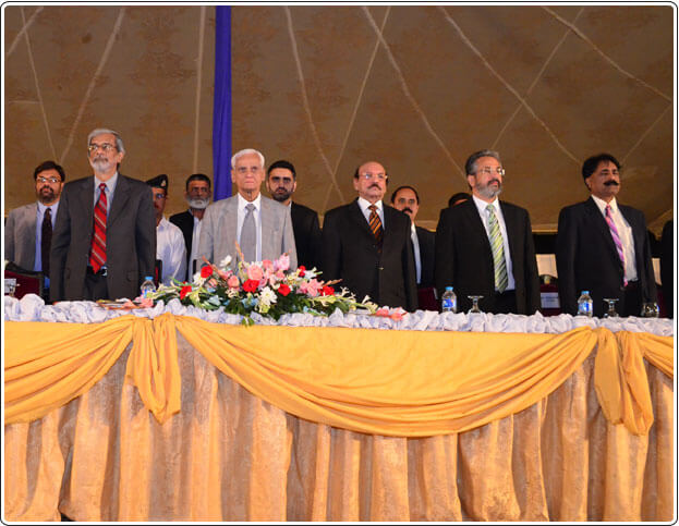 The dignitaries rising to their feet in respect of the national anthem